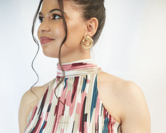 A person wearing a long flowy multicolored dress with a halter neck.